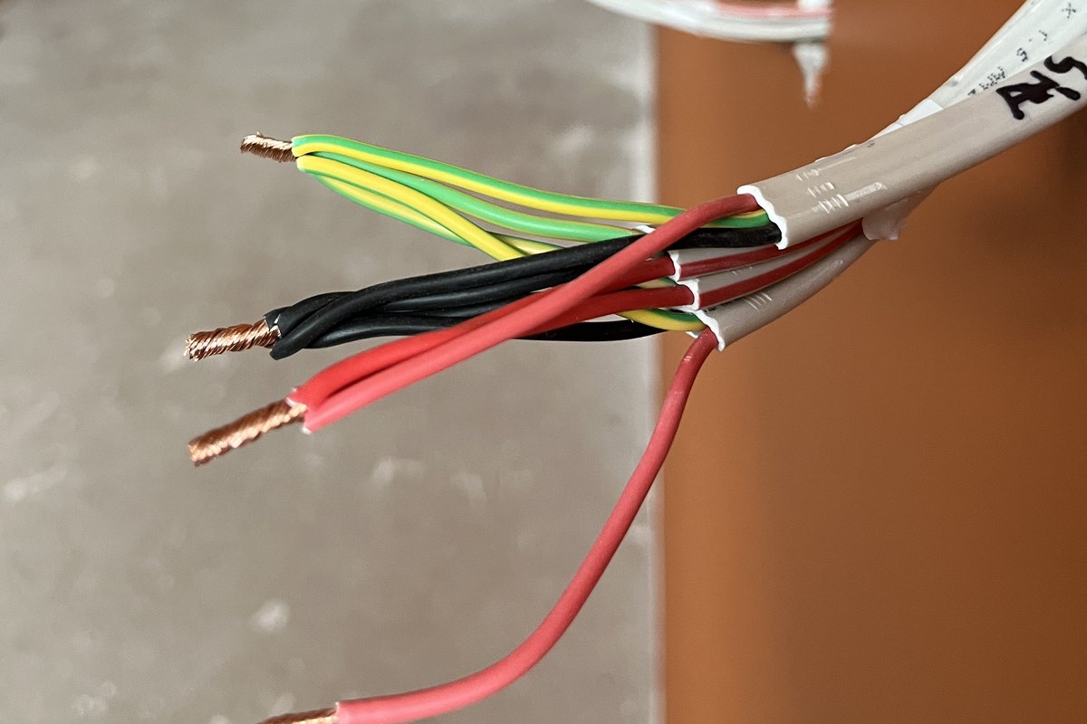 Close-up of electrical cable tails at a painted wall, sheath stripped back and cores fanned out ready to terminate, by SALTD Electrical